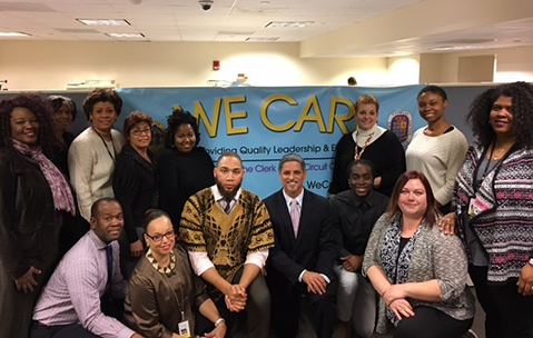 Clerk of Court Sydney Harrison and staff in front of We Care poster