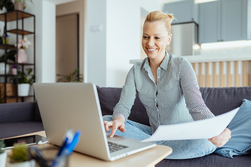 woman sitting at computer with paperwork smiling