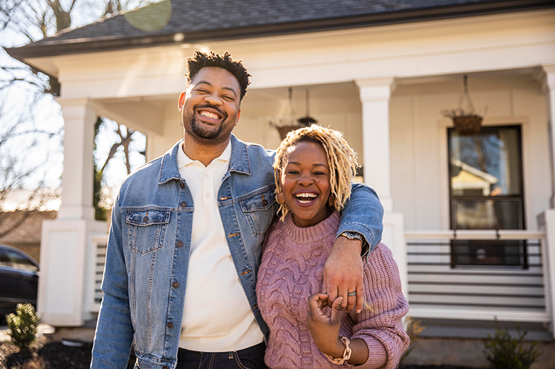 couple standing in front of house smiling