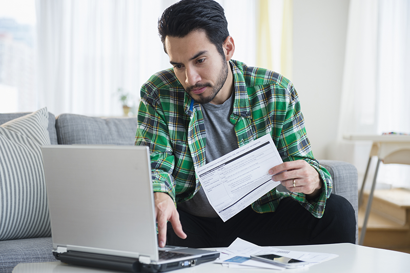 man sitting down holding paperwork looking at a screen