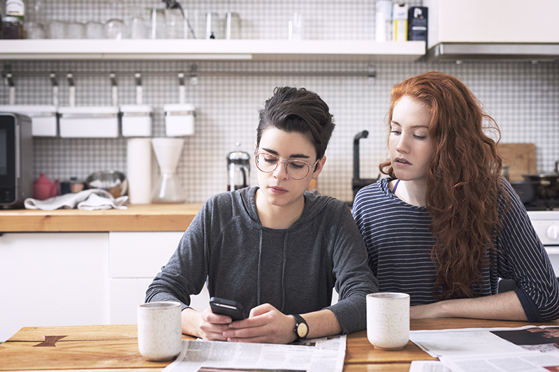 two women looking at a phone and paperwork together