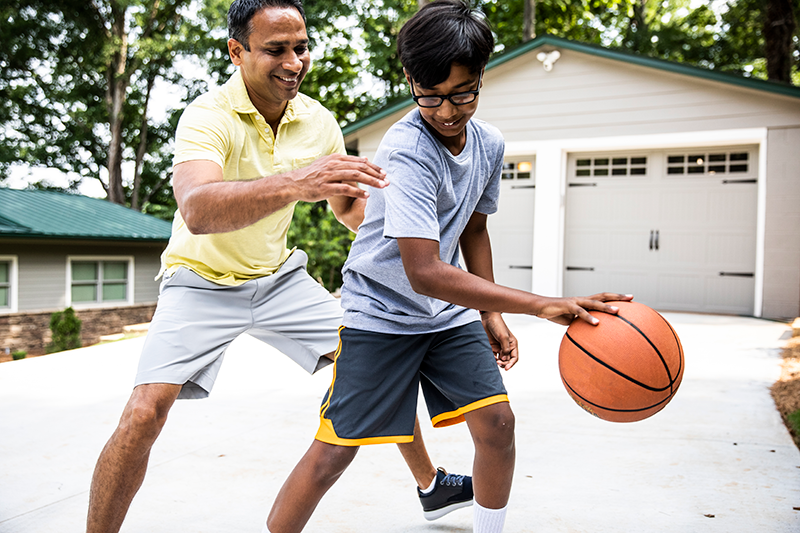 man and young boy playing basketball