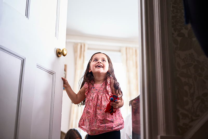 little girl opening door smiling