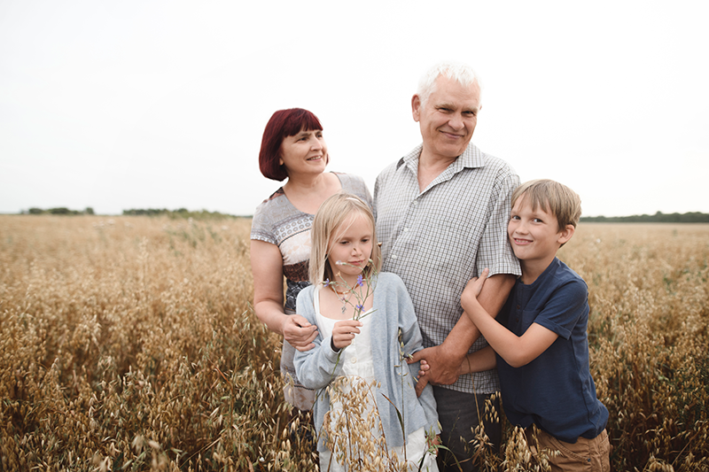 grandparents outside in a field hugging grandchildren and smiling