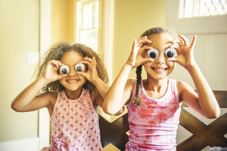 two young girls holding fake eyes up to their face