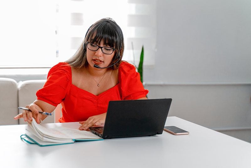 woman sitting at table with headset and computer