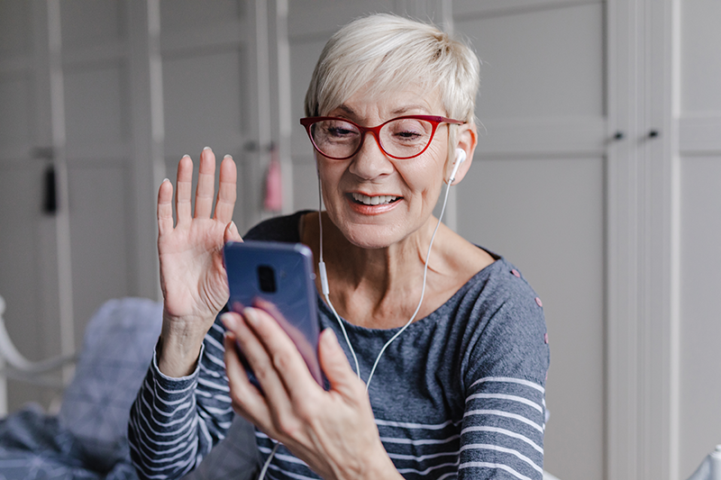 woman waving at her phone screen