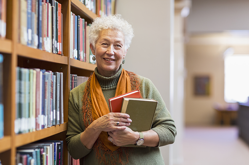 woman in library standing next to shelf of books